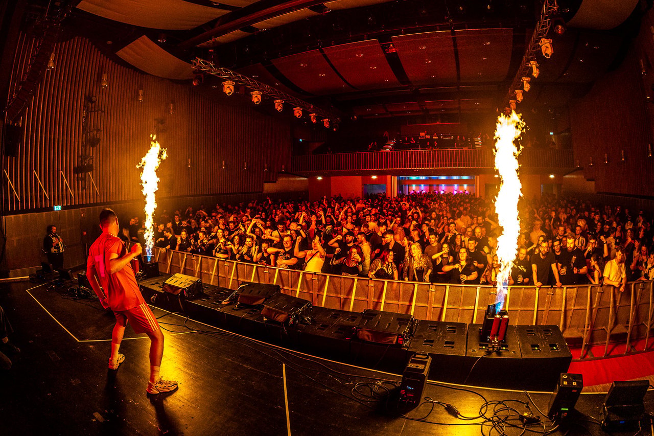 To DJs jubler på scenen foran en kæmpe menneskemængde og et lysshow.